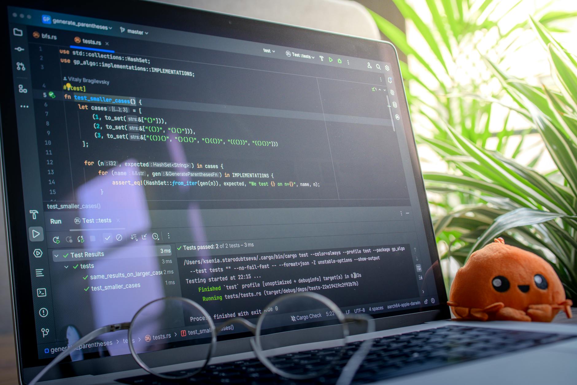 Laptop z wyświetlonym kodem obok pluszowej zabawki w jasnym biurze