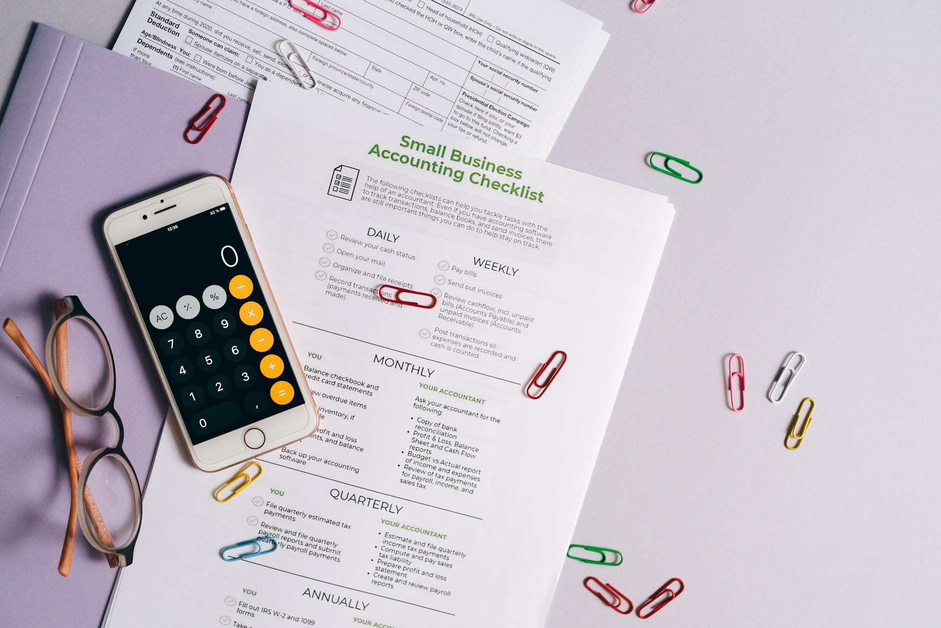Biurko z dokumentami księgowymi, smartfonem i okularami z góry
