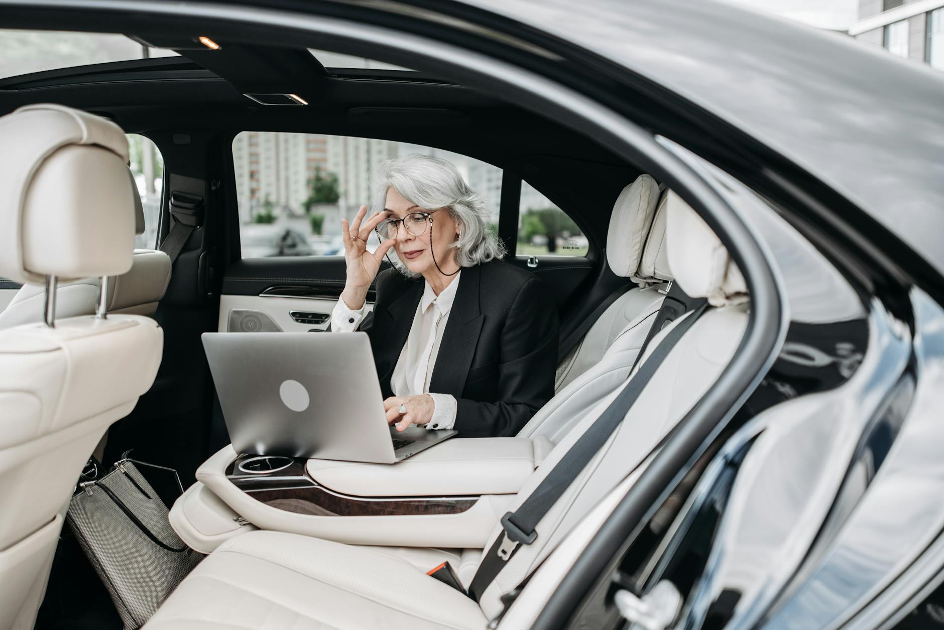 Bizneswoman w luksusowym aucie pracuje na laptopie w podróży delegacyjnej