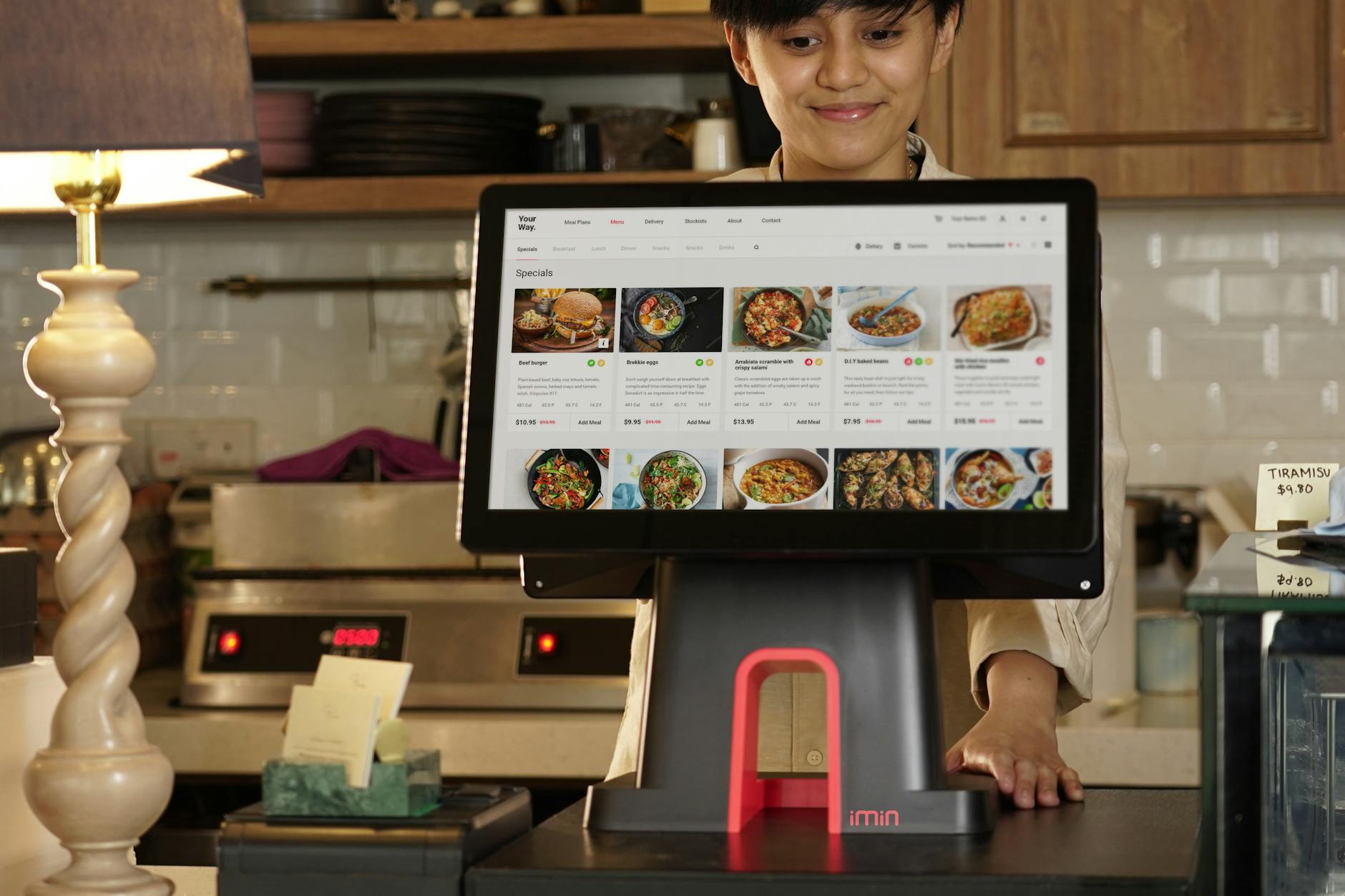 Kasjer w restauracji przyjmuje zamówienie na dotykowym ekranie systemu