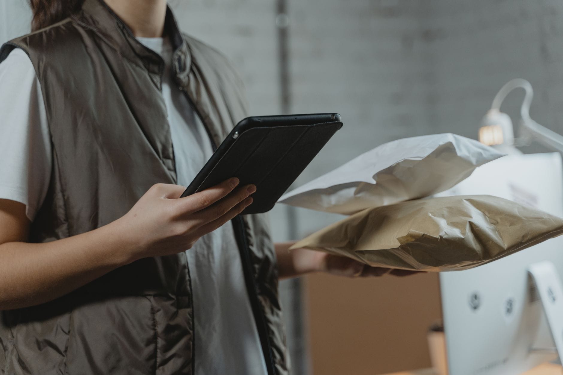 Jak przygotować opisy i atrybuty pod różne marketplace Osoba zarządzająca paczkami na tablecie w magazynie marketplace