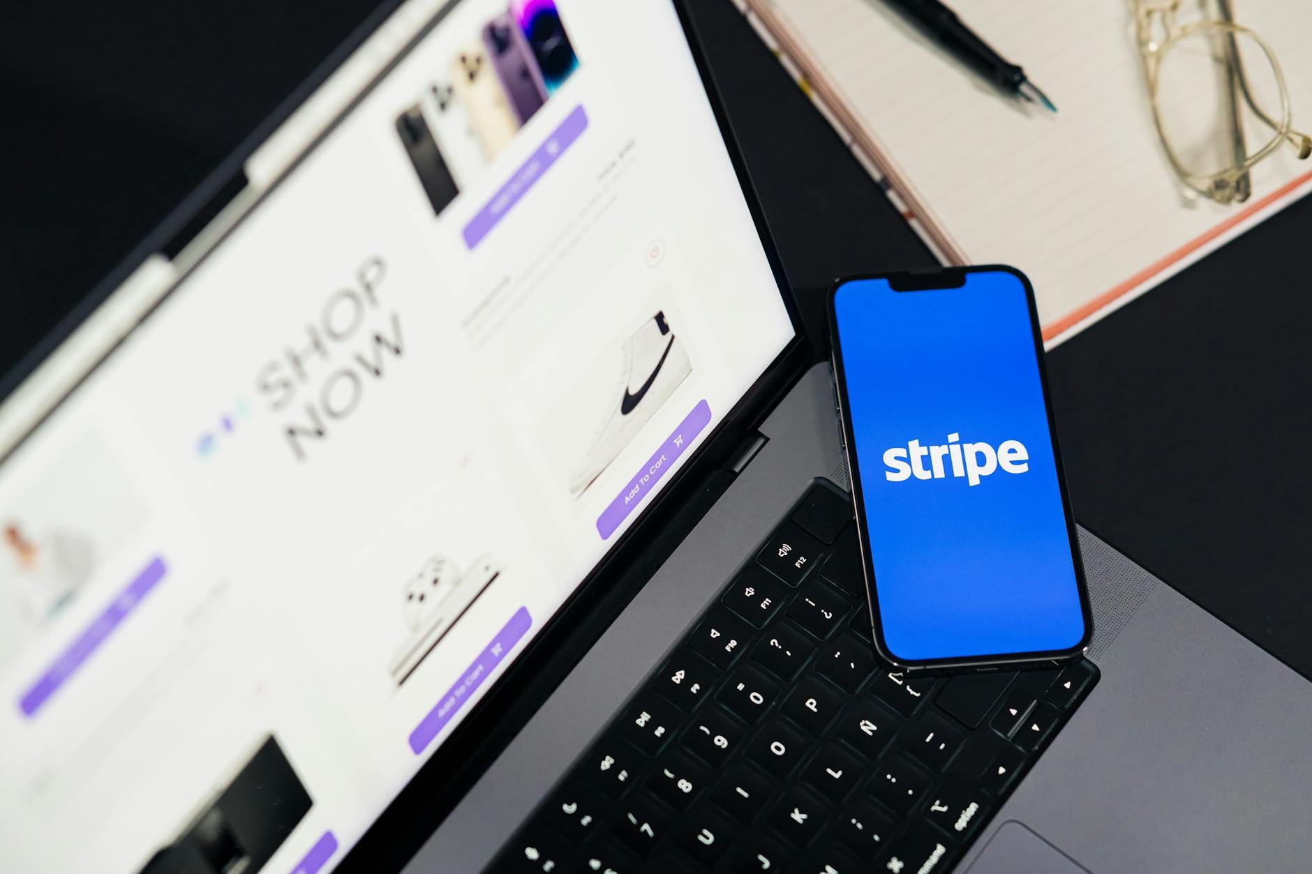 Telefon ze Stripe na tle laptopa z otwartym sklepem internetowym