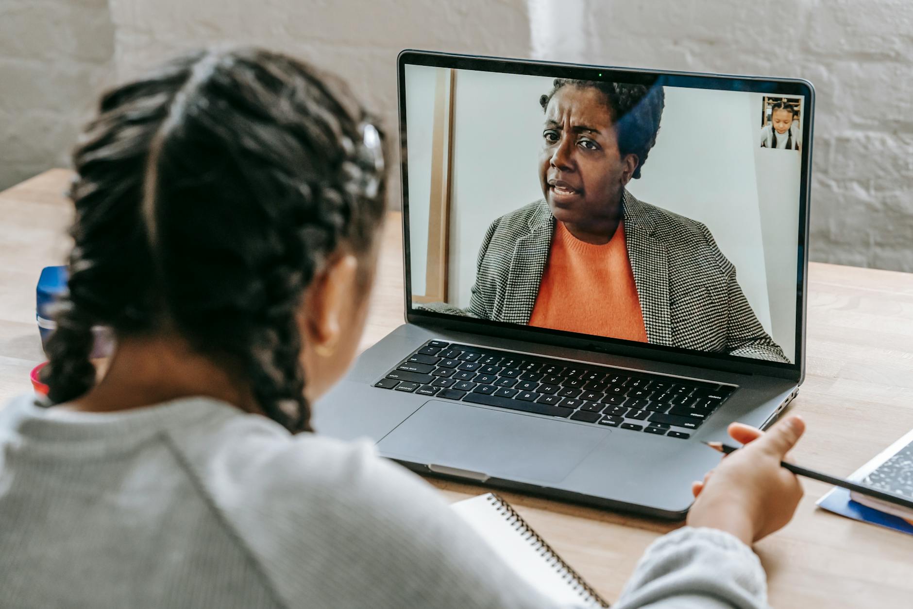 Uczennica przed laptopem omawia online test z nauczycielem