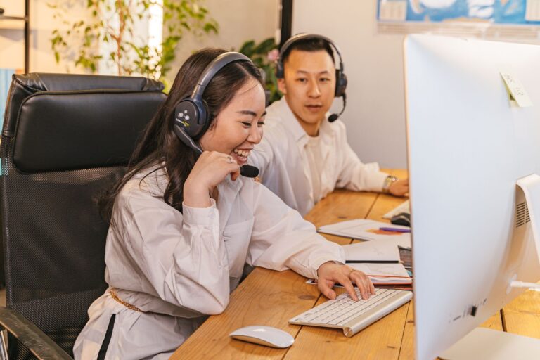 Dwóch agentów call center pracujących przy biurkach w słuchawkach